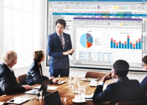 Consultoria de gestão empresarial com apresentação de dados financeiros em projeções de gráficos, com profissionais atentos ao especialista.