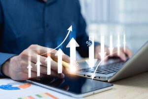 Gestor trabalhando em laptop com gráficos de desempenho e setas de crescimento digitalizadas representando análise financeira estratégica