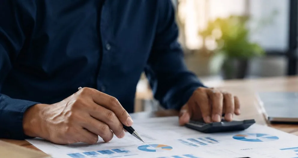 Profissional analisando gráficos financeiros em notebook durante gestão estratégica de custos empresarial.