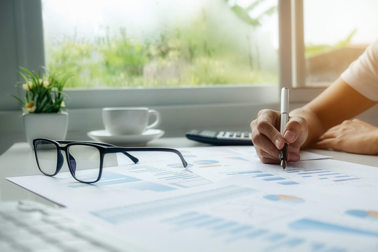 Pessoa analisando gráficos e relatórios financeiros sobre a mesa, ilustrando os benefícios do planejamento estratégico na tomada de decisões empresariais.