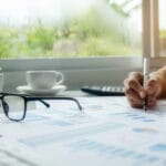 Pessoa analisando gráficos e relatórios financeiros sobre a mesa, ilustrando os benefícios do planejamento estratégico na tomada de decisões empresariais.