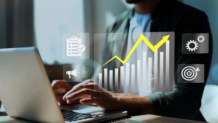 Pessoa digitando no notebook enquanto um gráfico ascendente relacionado à análise de custos aparece em destaque.