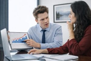 Homem apresenta gráfico de crescimento durante reunião de consultoria e gestão em situações de crise em ambiente corporativo.