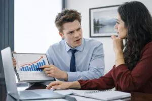 Homem apresenta gráfico de crescimento durante reunião de consultoria e gestão em situações de crise em ambiente corporativo.